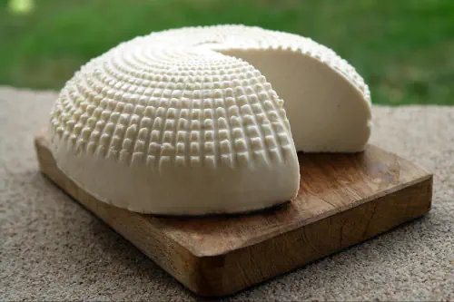 Un queso blanco con forma redonda sobre una tabla. Casa del Sur